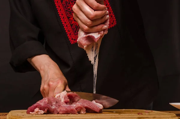 Las manos femeninas con un cuchillo en la mano cortan carne fresca en una mesa — Foto de Stock