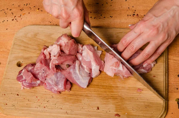 Las manos femeninas con un cuchillo en la mano cortan carne fresca en una mesa — Foto de Stock