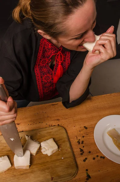 Una mujer está cortando carne ahumada en la cocina . — Foto de Stock