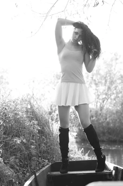 Ανοιχτό μοντέρνο πορτρέτο μιας όμορφης νεαρής γυναίκας με ένα καλοκαιρινό φόρεμα σε μια ηλιόλουστη μέρα με βάρκα. Μαύρη και λευκή φωτογραφία. — Φωτογραφία Αρχείου