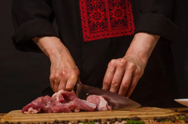 Las manos femeninas con un cuchillo en la mano cortan carne fresca en una mesa — Foto de Stock