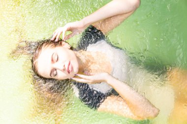 Güzel kadın model uzun akşam önlük giymiş, havuzda yatıyor ve sensually poz veriyor