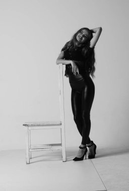 Çekici esmer güzellik sandalyede oturuyor.