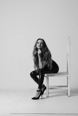 Çekici esmer güzellik sandalyede oturuyor.