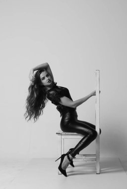 Çekici esmer güzellik sandalyede oturuyor.