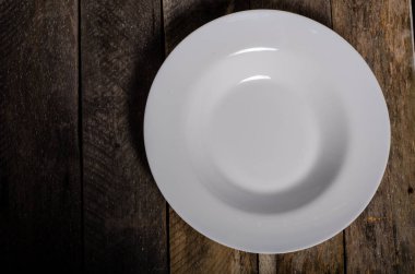 Kopya alanı ile ahşap arka plan üzerinde boş beyaz çanak ve beyaz masa örtüsü üst görünümü
