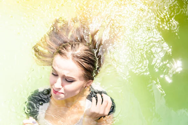 Güzel kadın model uzun akşam önlük giymiş, havuzda yatıyor ve sensually poz veriyor