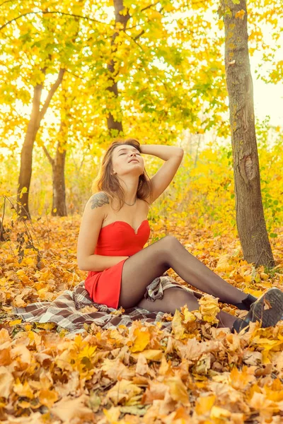 Uma mulher está posando na frente de uma câmera em um parque de outono. sessão de fotos de outono. Outono no parque . — Fotografia de Stock