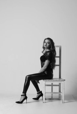 Çekici esmer güzellik sandalyede oturuyor.