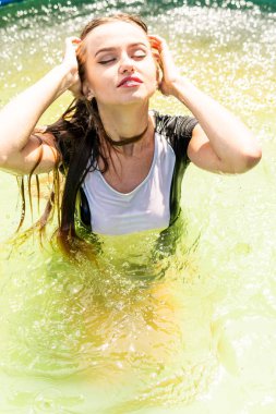 Güzel kadın model uzun akşam önlük giymiş, havuzda yatıyor ve sensually poz veriyor