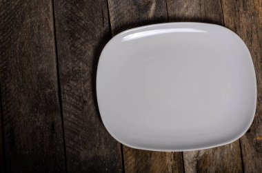 Kopya alanı ile ahşap arka plan üzerinde boş beyaz çanak ve beyaz masa örtüsü üst görünümü