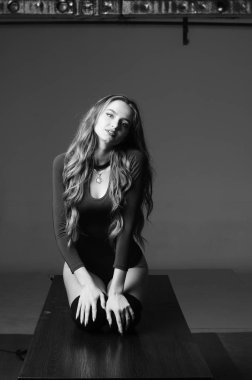 Büyük göğüslü seksi genç kadın. Siyah duvarda poz veren kız