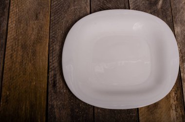 Kopya alanı ile ahşap arka plan üzerinde boş beyaz çanak ve beyaz masa örtüsü üst görünümü