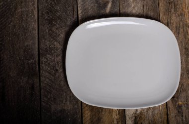 Kopya alanı ile ahşap arka plan üzerinde boş beyaz çanak ve beyaz masa örtüsü üst görünümü