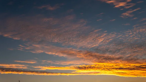 Himmelblaues und orangefarbenes Sonnenlicht durch die Wolken am Himmel — Stockfoto