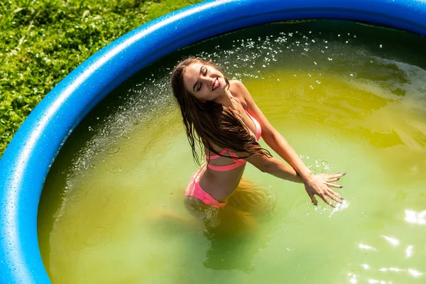 Moda de verano de mujer. Sexy Girl With Fit Curvy Body Shape, firmes nalgas, piel bronceada en hermoso bikini colorido traje de baño tomar el sol en la piscina en el complejo de lujo. Mujer caliente en traje de baño elegante — Foto de Stock