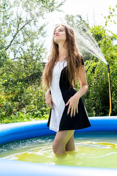 Hermosa modelo femenina vestida con largos vestidos de noche, se encuentra en la piscina y plantea sensualmente — Foto de Stock