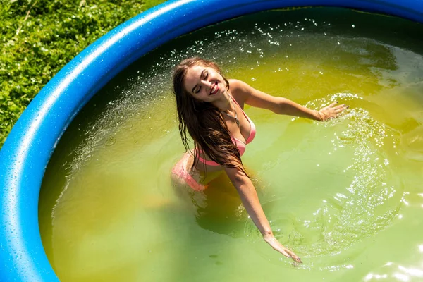 Moda de verano de mujer. Sexy Girl With Fit Curvy Body Shape, firmes nalgas, piel bronceada en hermoso bikini colorido traje de baño tomar el sol en la piscina en el complejo de lujo. Mujer caliente en traje de baño elegante — Foto de Stock