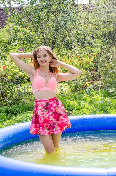 Schöne blonde Frau Modell mit erstaunlichen Körper steht im Pool in einem eleganten roten Badeanzug und im Hintergrund ist erstaunliche Aussicht auf das Meer und den Himmel. — Stockfoto