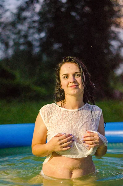 Chica en lencería y una camisa blanca se encuentra en una piscina con leche — Foto de Stock