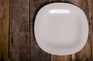 Kopya alanı ile ahşap arka plan üzerinde boş beyaz çanak ve beyaz masa örtüsü üst görünümü