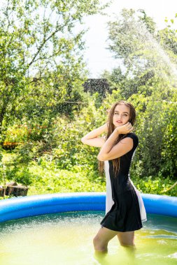 Güzel kadın model uzun akşam önlük giymiş, havuzda yatıyor ve sensually poz veriyor