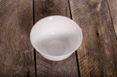 Kopya alanı ile ahşap arka plan üzerinde boş beyaz çanak ve beyaz masa örtüsü üst görünümü