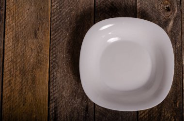 Kopya alanı ile ahşap arka plan üzerinde boş beyaz çanak ve beyaz masa örtüsü üst görünümü