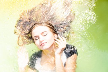 Güzel kadın model uzun akşam önlük giymiş, havuzda yatıyor ve sensually poz veriyor