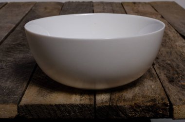 Kopya alanı ile ahşap arka plan üzerinde boş beyaz çanak ve beyaz masa örtüsü üst görünümü