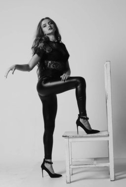 Çekici esmer güzellik sandalyede oturuyor.