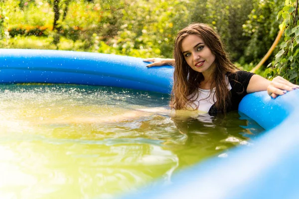 Schönes weibliches Model in langen Abendkleidern, liegt im Pool und posiert sinnlich — Stockfoto
