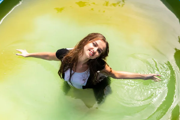 Beautiful female model dressed in long evening gowns, lies in the pool and sensually poses — Stock Photo, Image