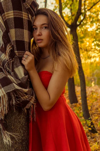 Uma mulher está posando na frente de uma câmera em um parque de outono. sessão de fotos de outono. Outono no parque . — Fotografia de Stock