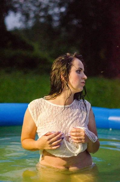 Chica en lencería y una camisa blanca se encuentra en una piscina con leche —  Fotos de Stock