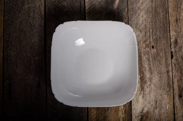 コピースペース付きの木製の背景に空白の白い皿と白いテーブルクロスのトップビュー — ストック写真