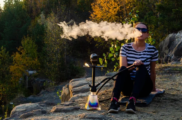 Een vrouw die shisha (hookah) rookt zittend aan zee. Meeuwen op de achtergrond. — Stockfoto