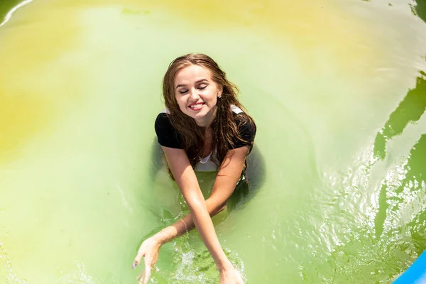 Beautiful female model dressed in long evening gowns, lies in the pool and sensually poses — Stock Photo, Image