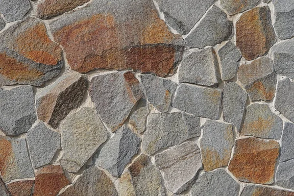 Decorative wall of artificial torn stone in brown tones. Stone masonry in geometric pattern as background or texture. — Stock Photo, Image