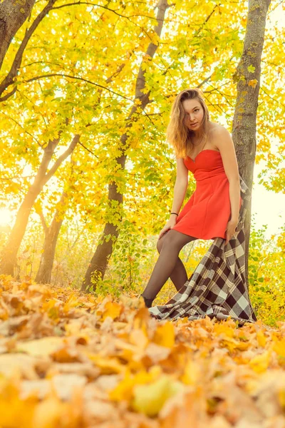 En kvinna poserar framför en kamera i en park på hösten. höst foto shoot. Hösten i parken. — Stockfoto