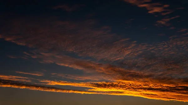 Himmelblaues und orangefarbenes Sonnenlicht durch die Wolken am Himmel — Stockfoto