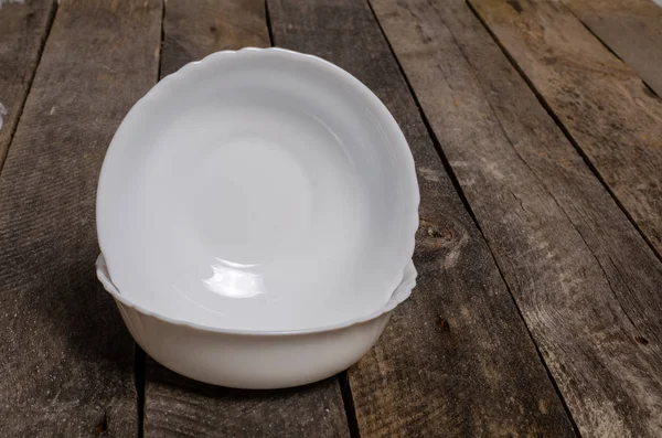 Top view of blank white dish and white stablecloth on a wood background with copy space — стоковое фото