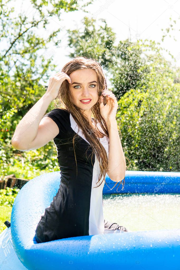 Beautiful female model dressed in long evening gowns, lies in the pool and sensually poses