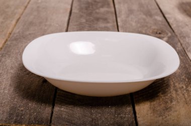 Kopya alanı ile ahşap arka plan üzerinde boş beyaz çanak ve beyaz masa örtüsü üst görünümü