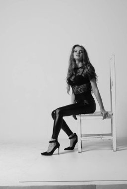 Çekici esmer güzellik sandalyede oturuyor.