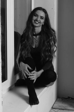 Büyük göğüslü seksi genç kadın. Siyah duvarda poz veren kız