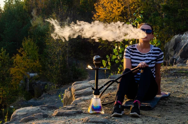 Een vrouw die shisha (hookah) rookt zittend aan zee. Meeuwen op de achtergrond. — Stockfoto