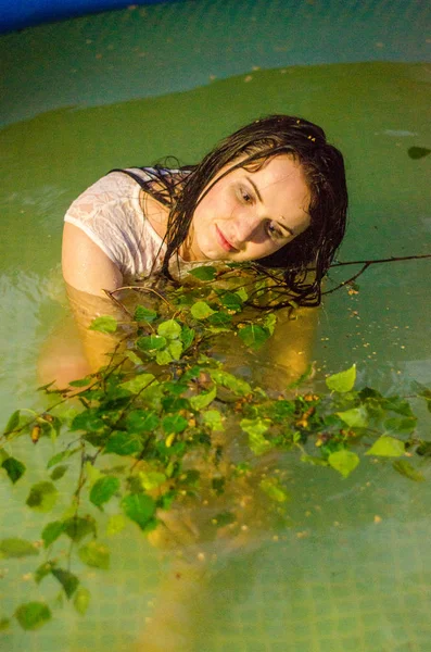 Meisje in lingerie en een wit overhemd ligt in een pool met melk — Stockfoto