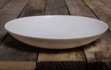 Kopya alanı ile ahşap arka plan üzerinde boş beyaz çanak ve beyaz masa örtüsü üst görünümü