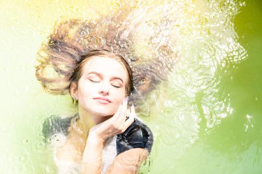 Güzel kadın model uzun akşam önlük giymiş, havuzda yatıyor ve sensually poz veriyor